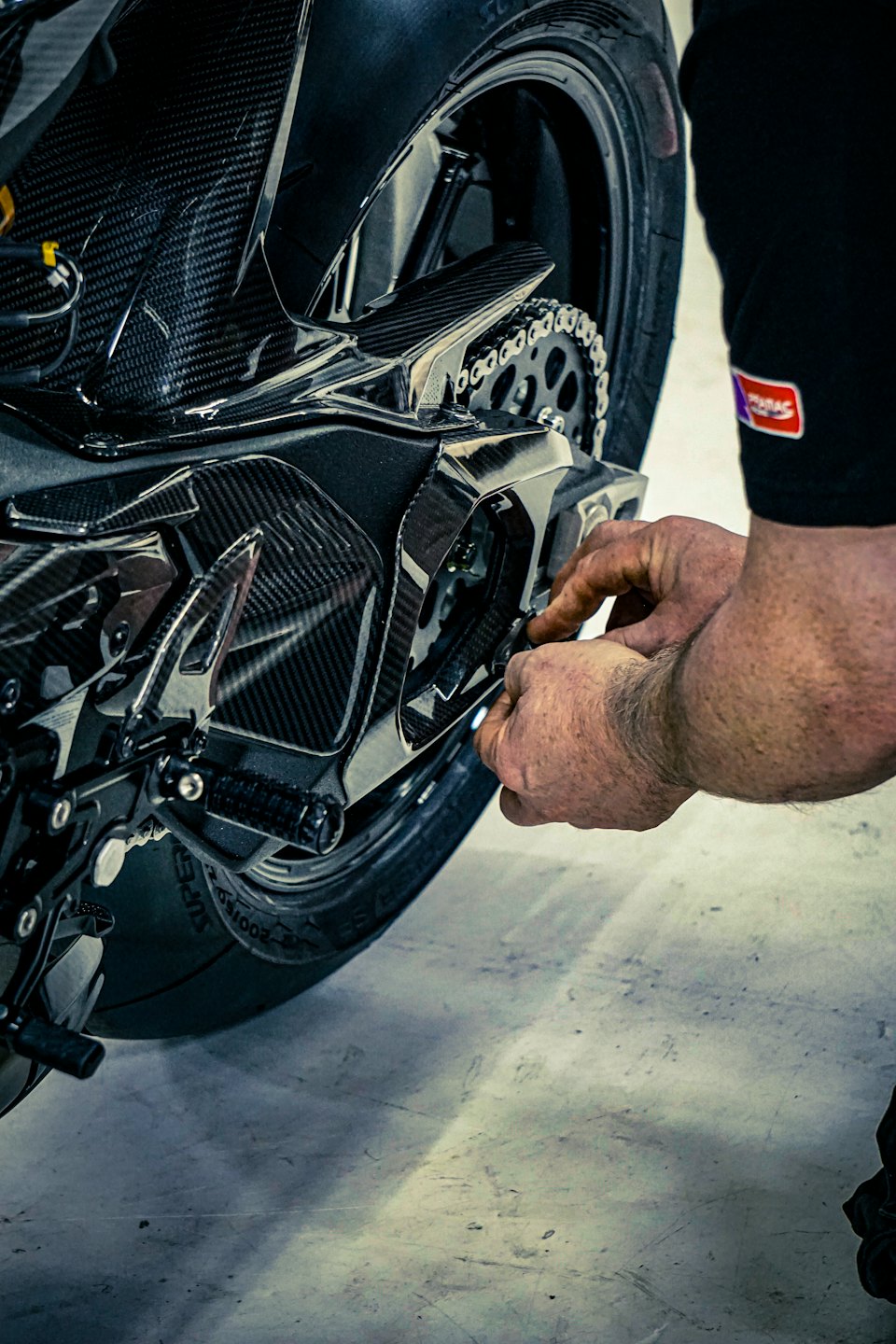 Mechanik reguluje łańcuch i zębatkę w motocyklu.
