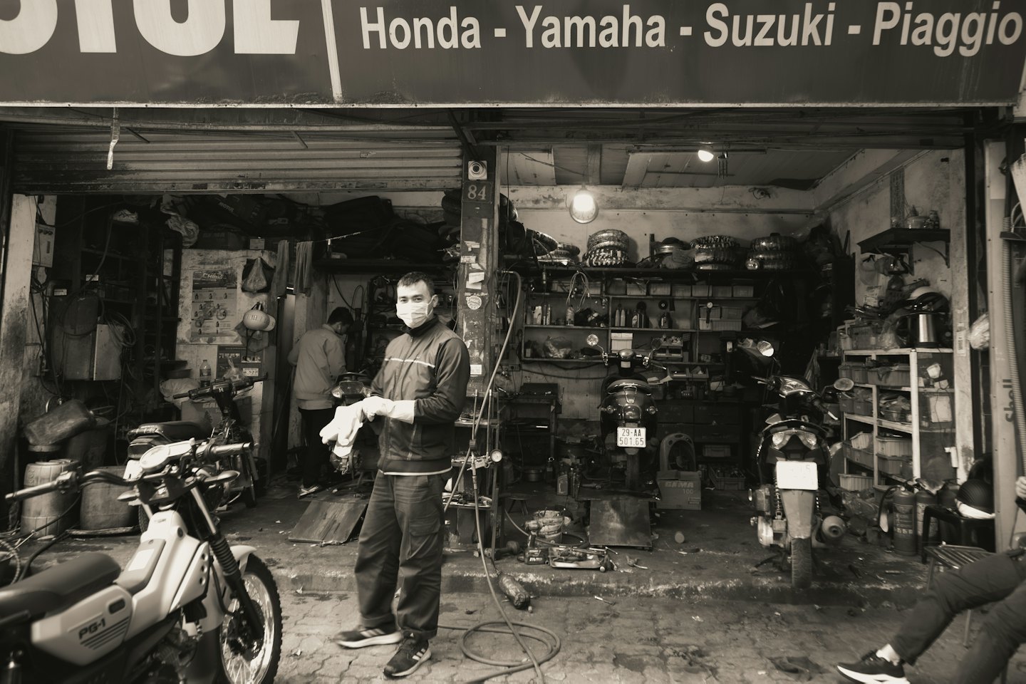 Mechanik w masce stoi w warsztacie motocyklowym.